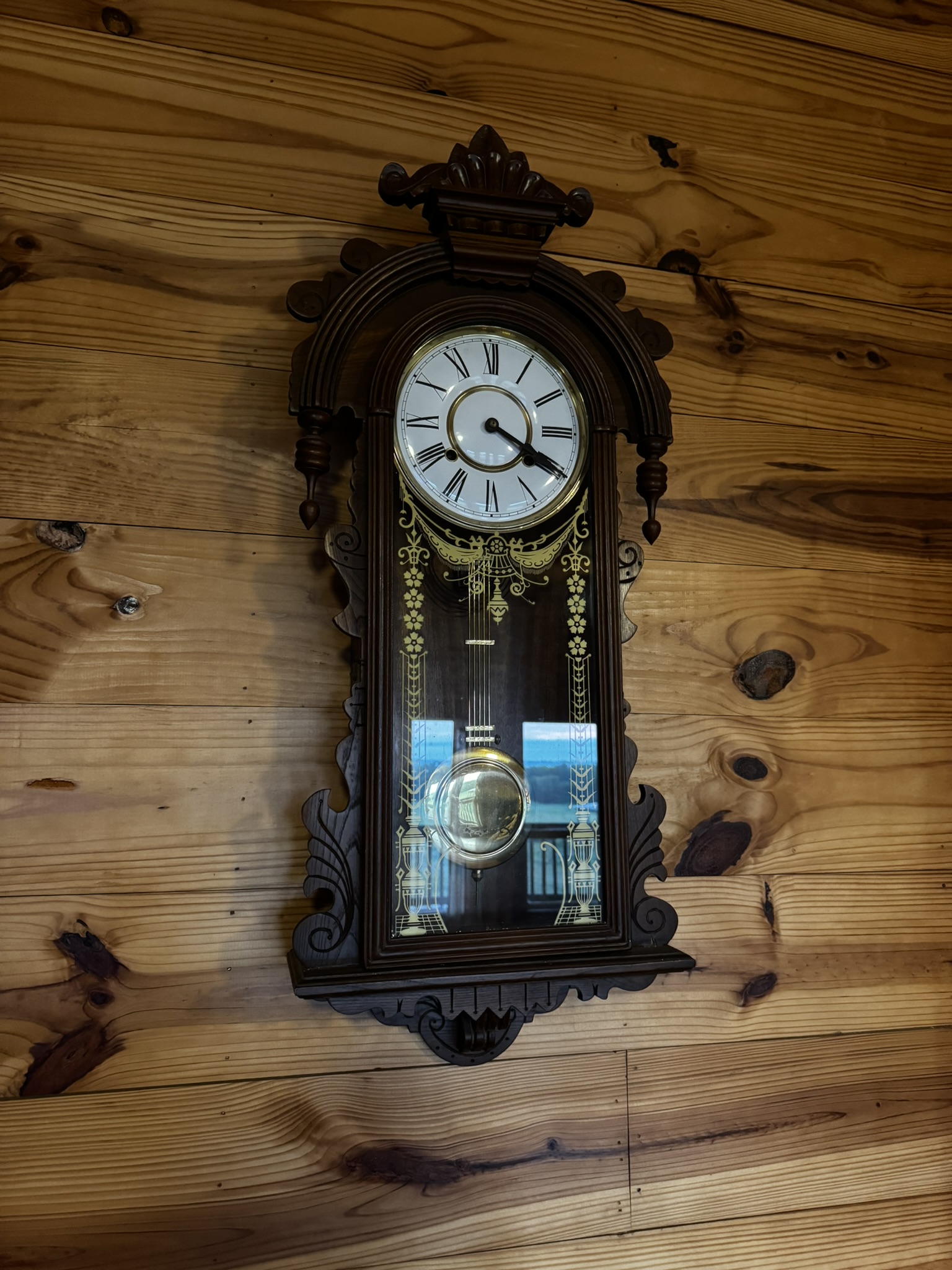 Antique gingerbread wall clock on wood-paneled wall